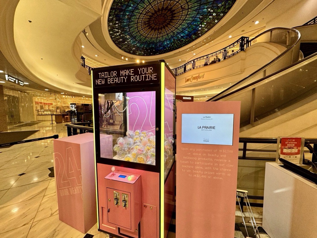 香港高級商場中庭內一部粉紅色訂製夾公仔機,旁邊有品牌告示牌,機內載滿扭蛋
